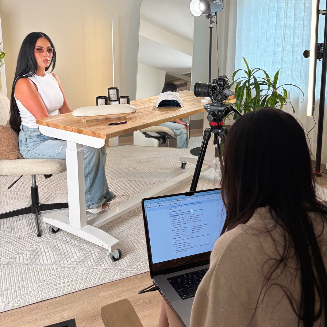 Founder video production setup with a camera on a tripod, laptop, and people around in a room.