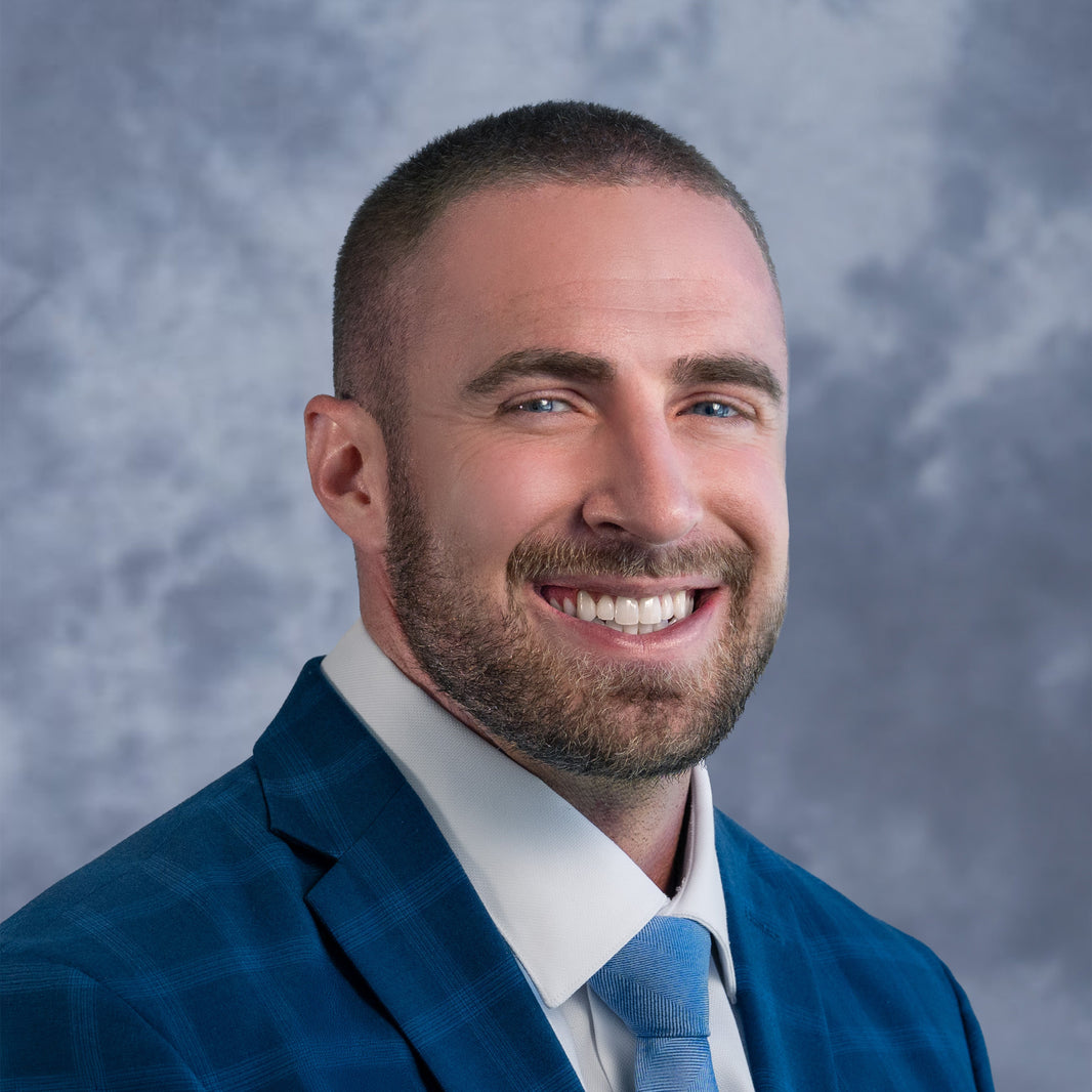Man wearing a blue suit and tie against a gray background